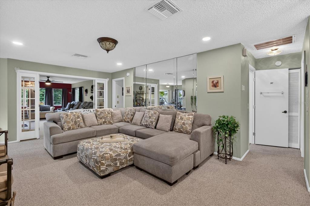 A living room features a large gray sectional sofa, mirrored wall panels, and carpeted floors — 10508 QUIMBY DRIVE, PORT RICHEY, FL