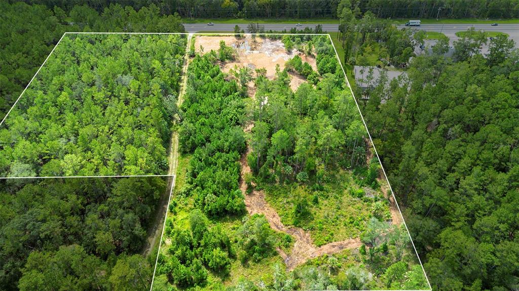 An aerial view shows a large, partially cleared wooded lot bordered by a road — 10951 E HIGHWAY 40, SILVER SPRINGS, FL