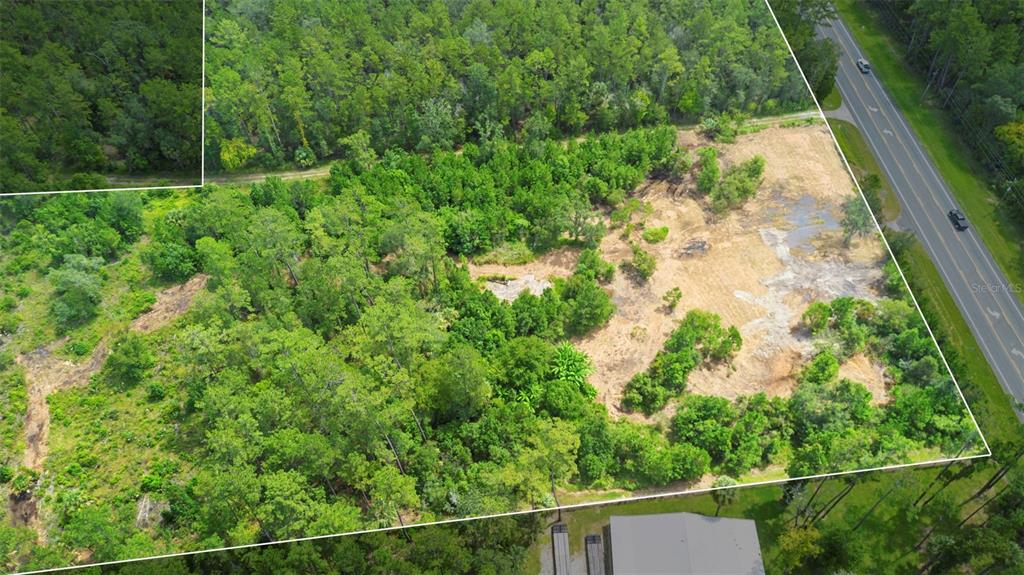 An aerial view shows a partially cleared, wooded lot adjacent to a paved road — 10951 E HIGHWAY 40, SILVER SPRINGS, FL