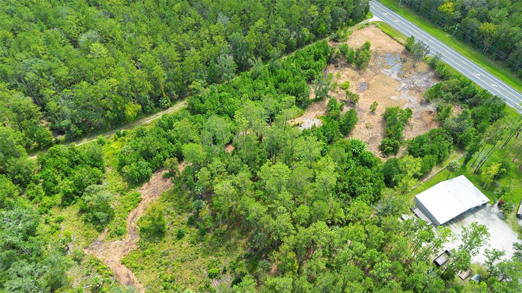 An aerial view shows a wooded lot with a cleared area and a metal building — 10951 E HIGHWAY 40, SILVER SPRINGS, FL