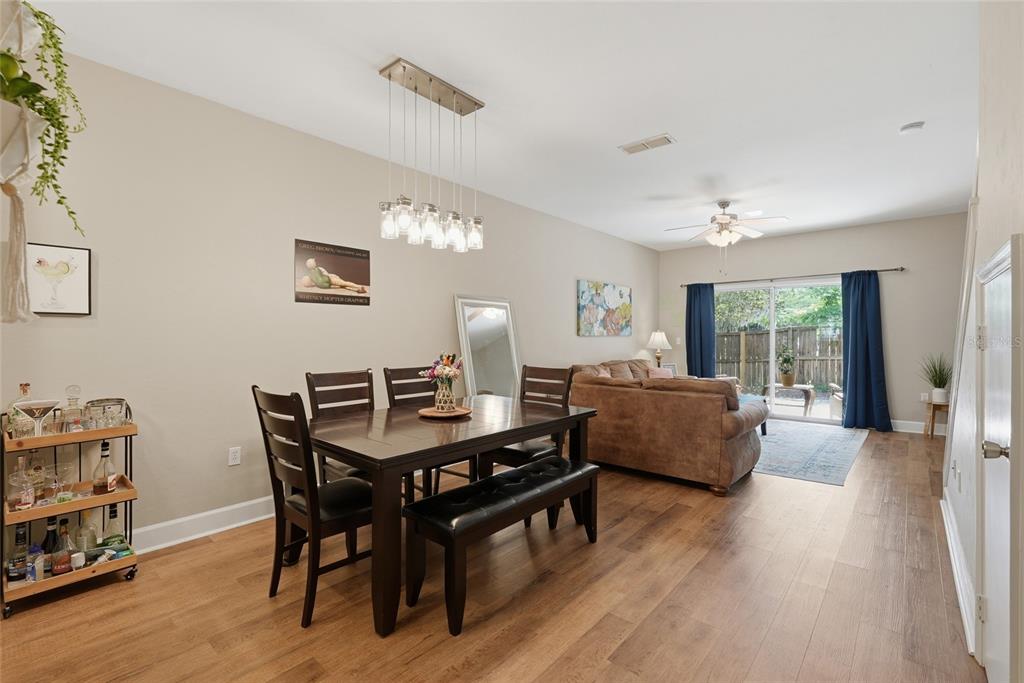 A dining area with a wooden table and bench opens into a living room with sliding doors — 935 NW 21ST AVENUE UNIT 935, GAINESVILLE, FL