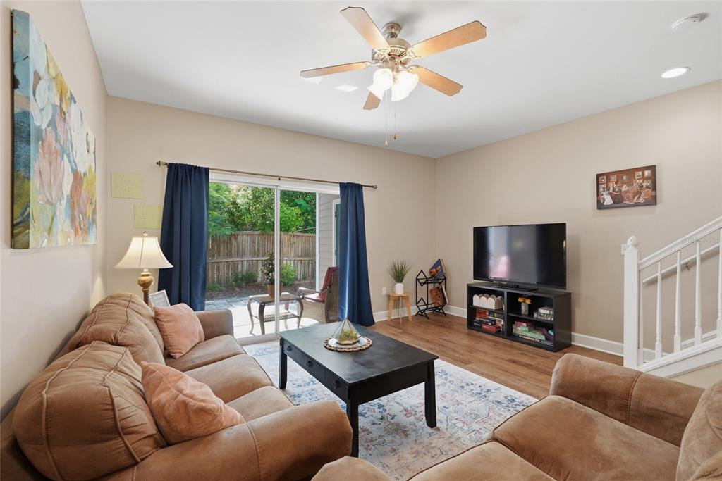 A living room features a brown sofa, a coffee table, a television, and sliding glass doors — 935 NW 21ST AVENUE UNIT 935, GAINESVILLE, FL