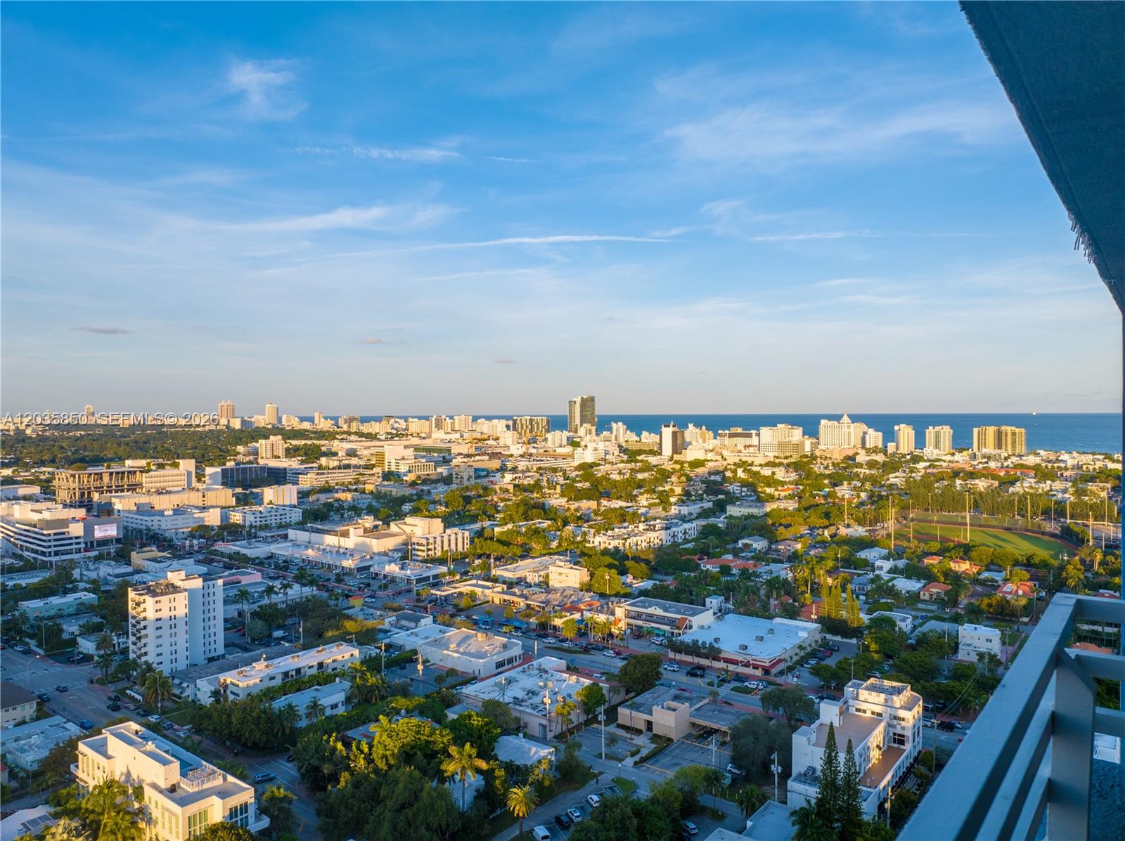 A high-angle view of a city skyline with buildings, trees, and the ocean beyond — 1330 West Ave # 3009, Miami Beach FL 33139, MIAMI BEACH, FL