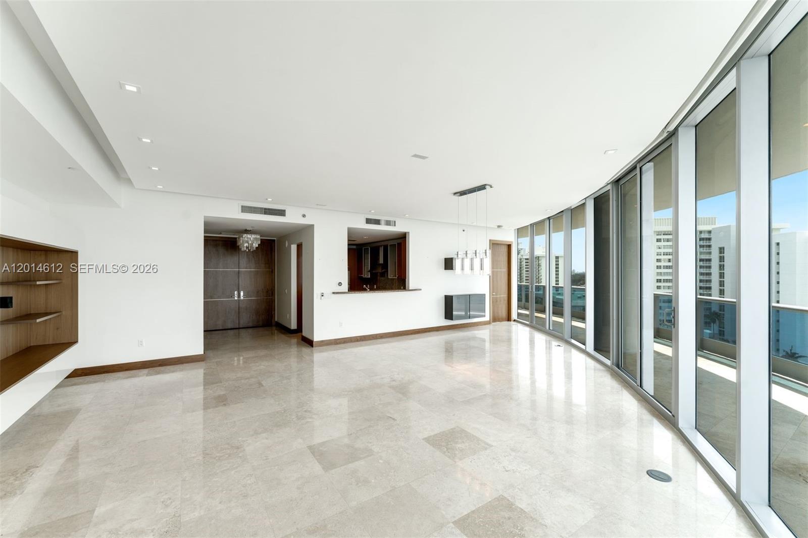 A bright, open-plan living area features marble flooring, floor-to-ceiling windows, and a kitchen pass-through — 5959 Collins Ave # 1001, Miami Beach FL 33140, MIAMI BEACH, FL