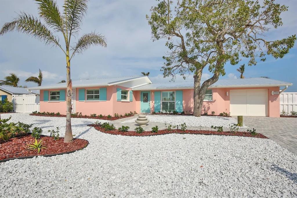 A single-story pink house with turquoise shutters, a white gravel yard, and a palm tree — 605 CONCORD LANE, HOLMES BEACH, FL