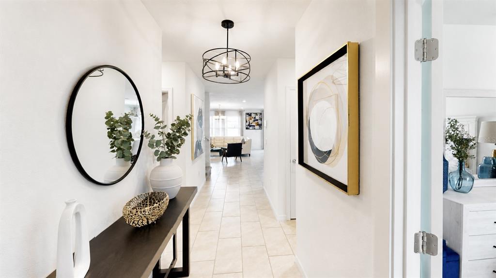 A bright hallway features a console table, round mirror, and a modern chandelier — 3884 CAPRI COAST DRIVE, PLANT CITY, FL