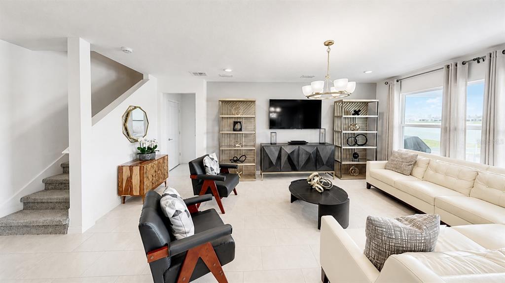 A modern living room features white tile floors, a white sofa, and two black armchairs — 3884 CAPRI COAST DRIVE, PLANT CITY, FL