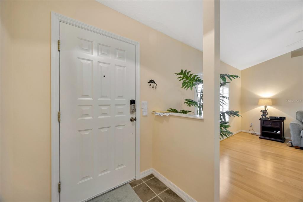 An entryway with a white door, tile flooring, and a view into a living room — 37157 FOXRUN PLACE, ZEPHYRHILLS, FL