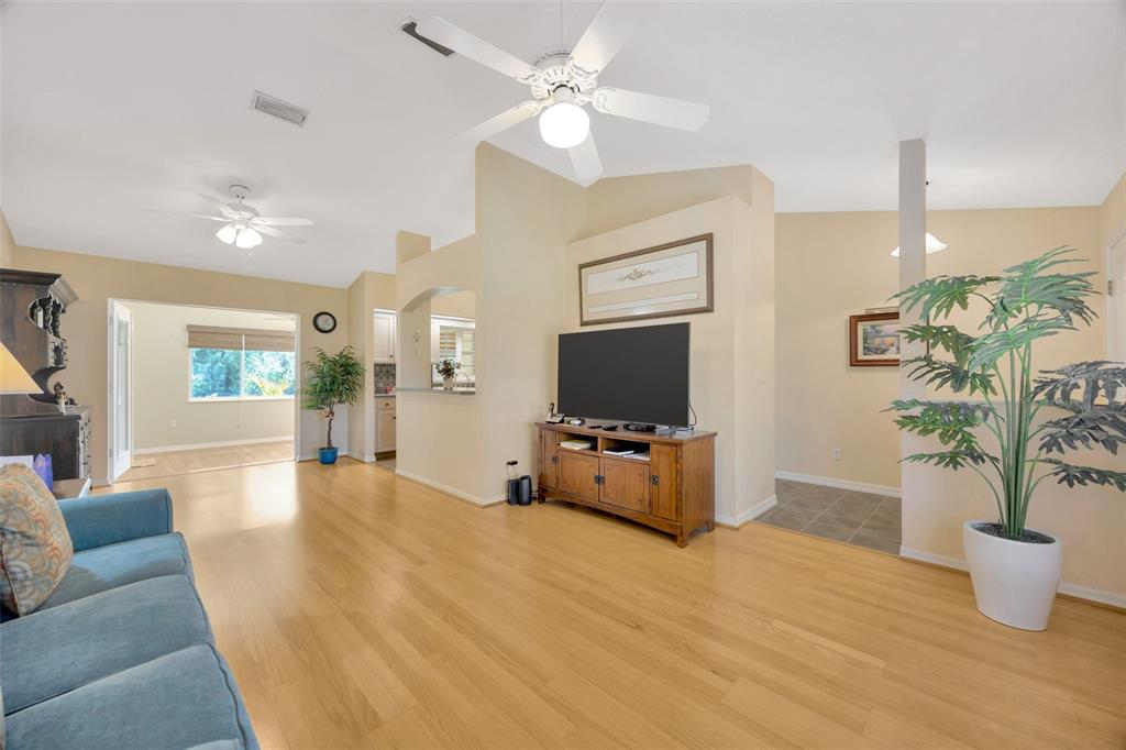 A living room with light wood floors, a ceiling fan, and a television on a console — 37157 FOXRUN PLACE, ZEPHYRHILLS, FL