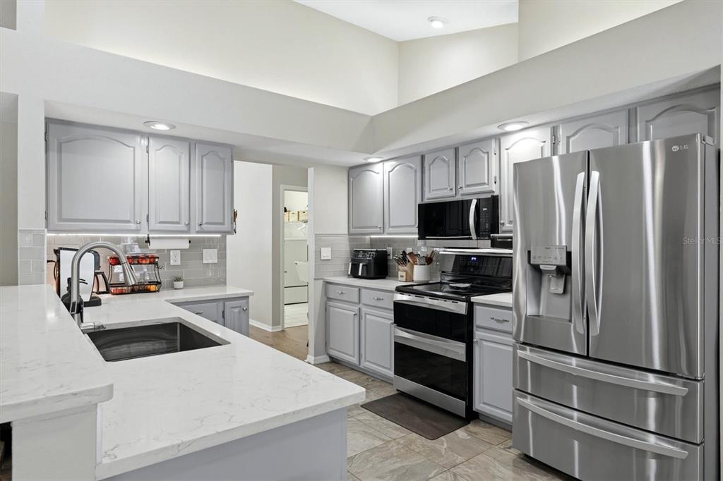 A kitchen with grey cabinets, stainless steel appliances, and white marble-look countertops — 4917 SE BROWN ROAD, ARCADIA, FL