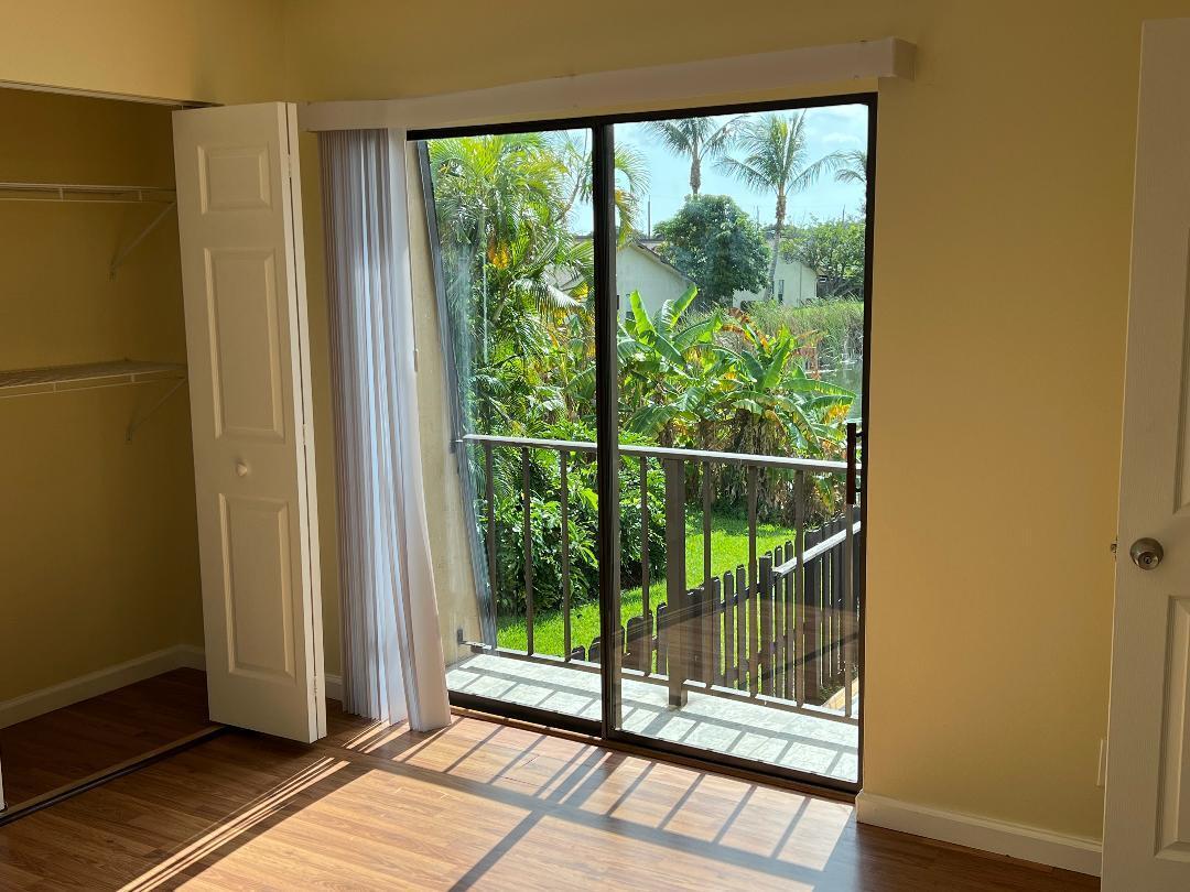 A bedroom with wood-look flooring, a closet, and a sliding glass door leading to a balcony — 6003 Waterview Circle, Palm Springs FL 33461, PALM SPRINGS, FL