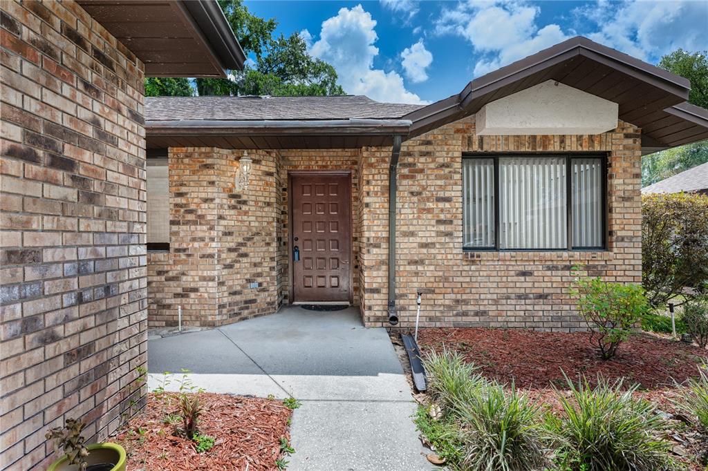 A brick house exterior features a recessed front door with square panels and a window — 109 WATERWOOD DRIVE, YALAHA, FL