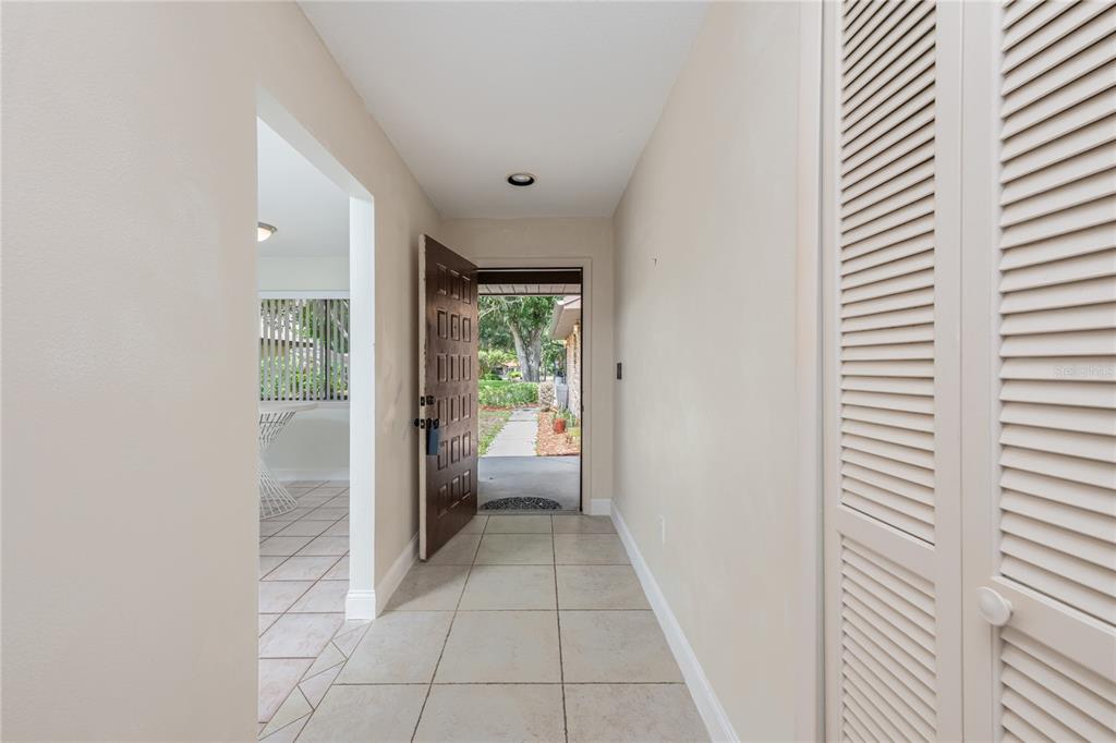 An entryway with tile flooring, a louvered closet door, and an open front door — 109 WATERWOOD DRIVE, YALAHA, FL