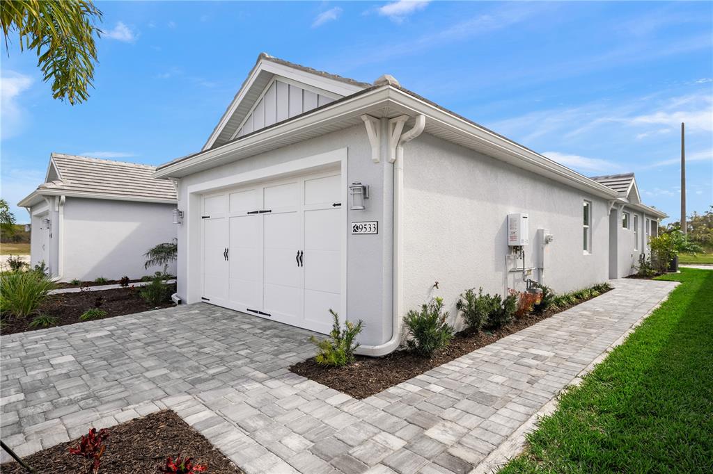 A white stucco house exterior features a garage, a paved walkway, and landscaping — 9533 LUNAR DOVE DRIVE, SARASOTA, FL