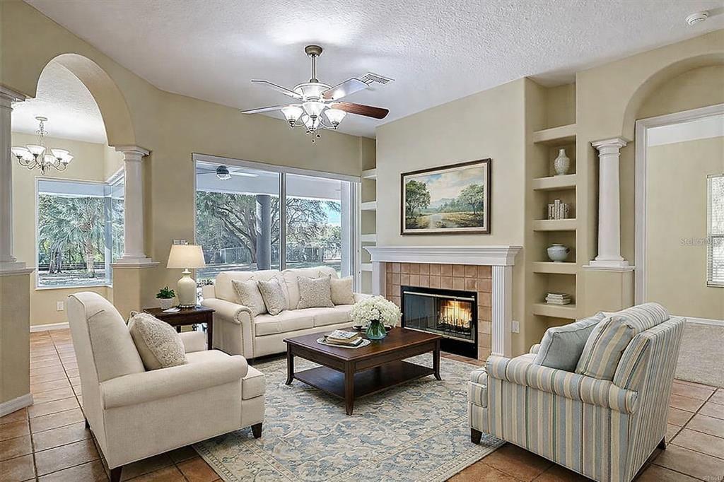 A living room features a fireplace, built-in shelving, tile flooring, and a ceiling fan — 949 HAWK LANDING, FRUITLAND PARK, FL