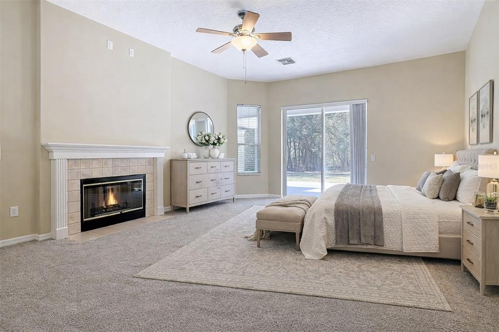 A spacious bedroom features a fireplace, a large bed, and sliding glass doors to outside — 949 HAWK LANDING, FRUITLAND PARK, FL
