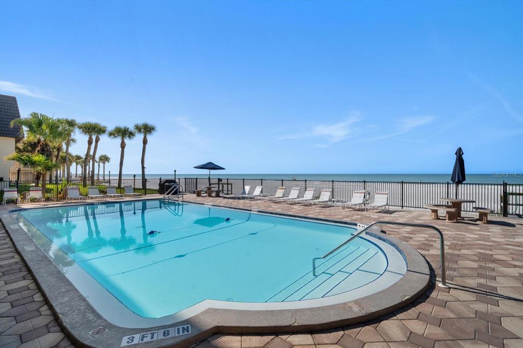 A swimming pool with a shallow entry area overlooks the beach and ocean — 60 GULF BOULEVARD UNIT 201, INDIAN ROCKS BEACH, FL