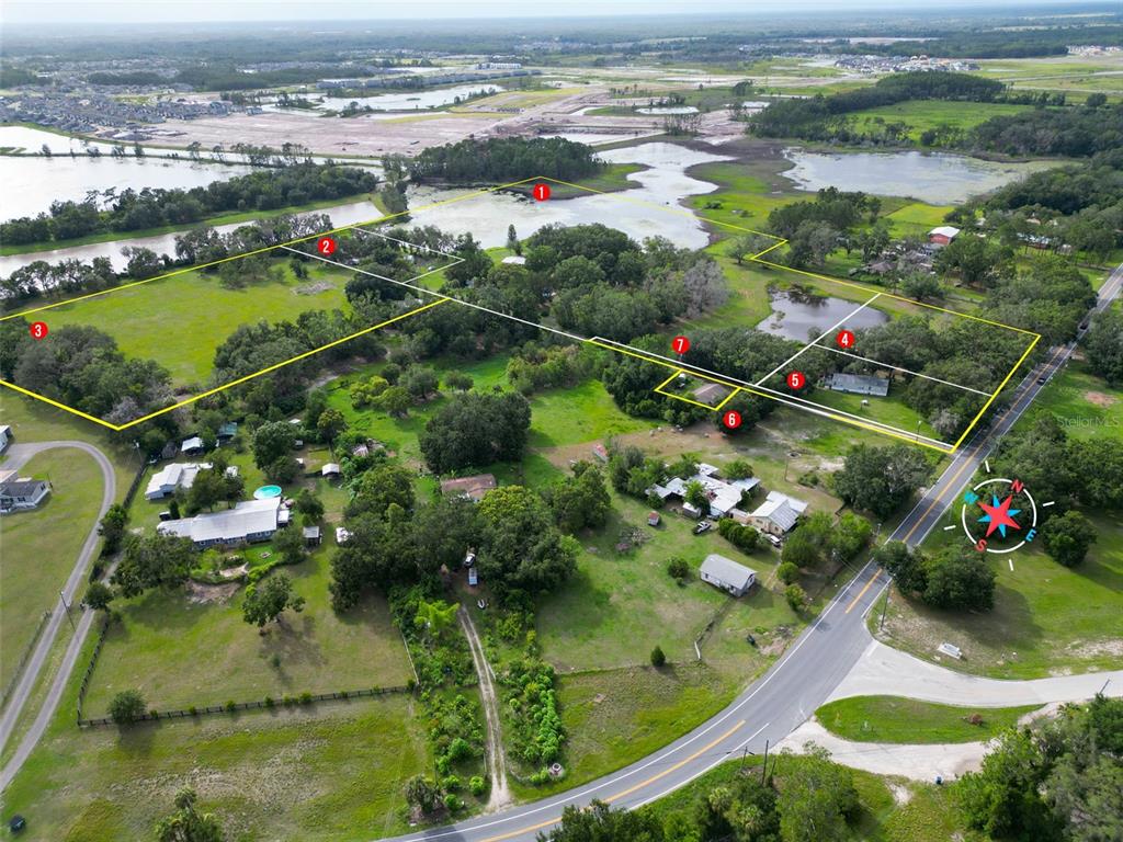An aerial view shows a large plot of land with several houses and a pond — 22839 BUNGALOW LANE, LAND O LAKES, FL