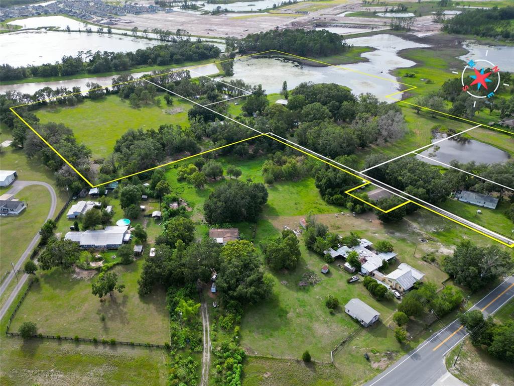An aerial view shows several houses on a large, grassy lot with trees and ponds — 22839 BUNGALOW LANE, LAND O LAKES, FL