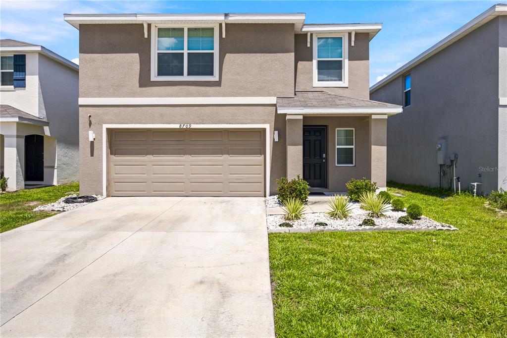 A two-story suburban house with a tan stucco exterior, a two-car garage, and landscaping — 8709 SW 46TH AVENUE, OCALA, FL