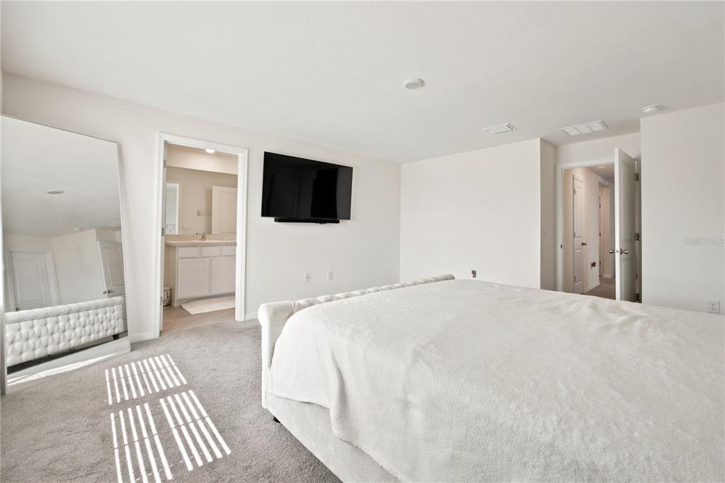 A bedroom features a tufted bed, a large floor mirror, and an attached bathroom — 8709 SW 46TH AVENUE, OCALA, FL