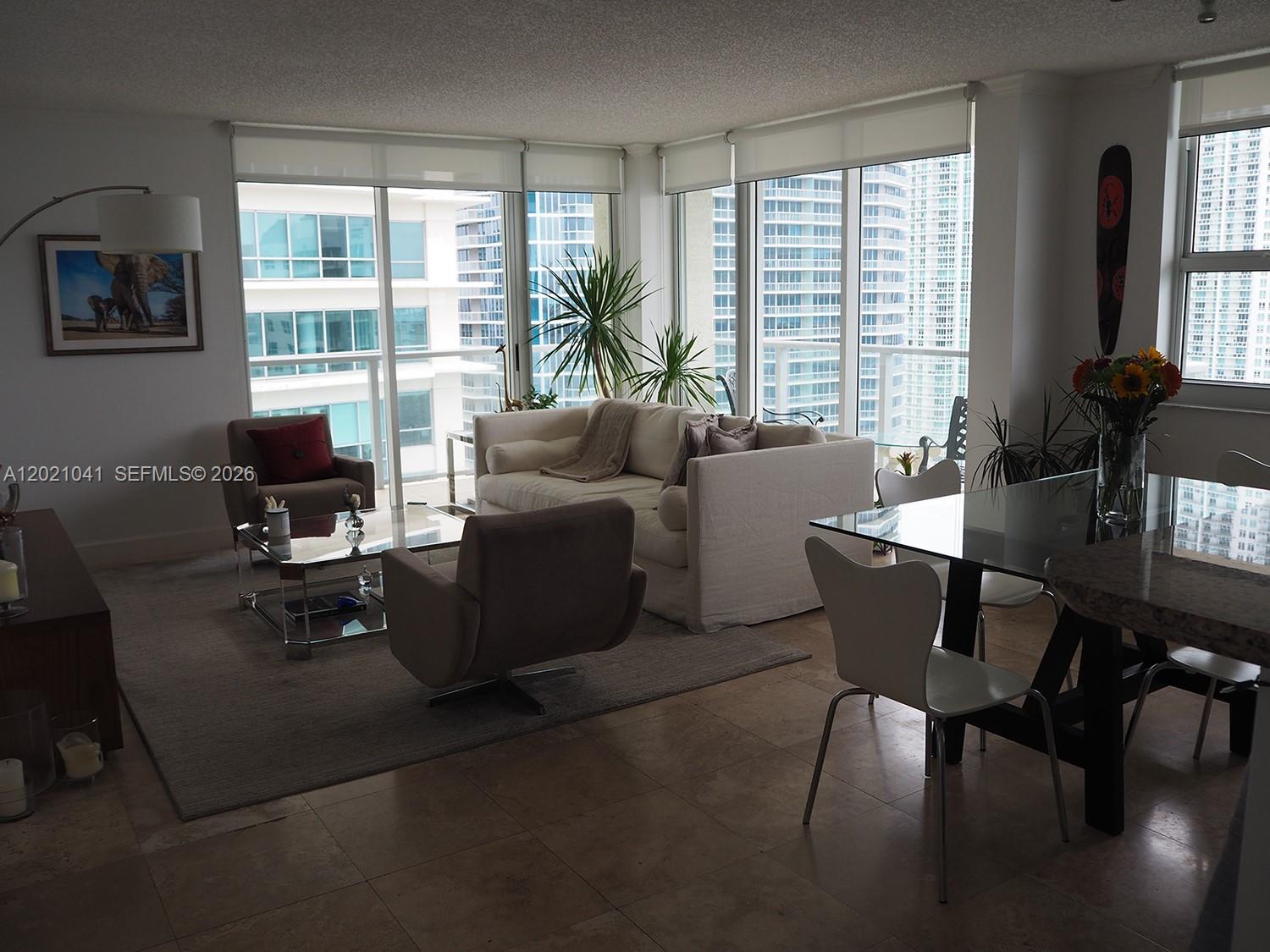 A living and dining area features floor-to-ceiling windows, tile flooring, and modern furniture — 1155 BRICKELL BAY DR # 3102, Miami FL 33131, MIAMI, FL
