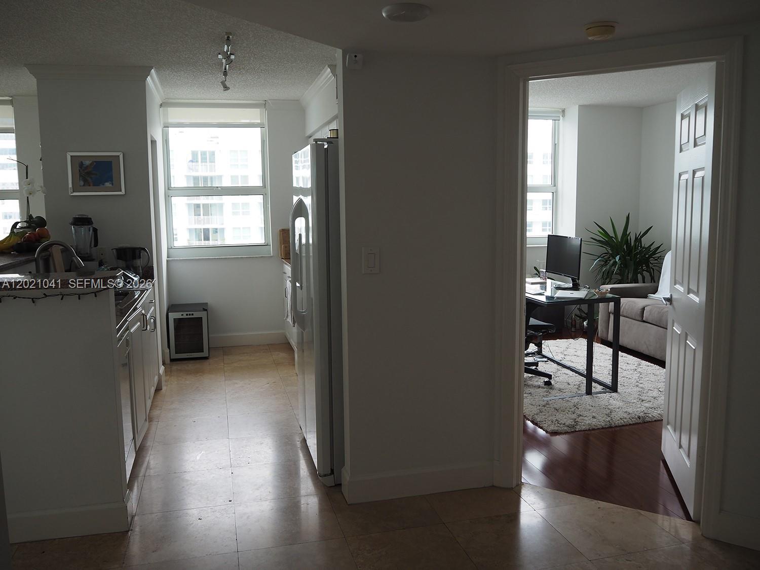 A kitchen with tile floors leads to an adjacent room containing a desk and sofa — 1155 BRICKELL BAY DR # 3102, Miami FL 33131, MIAMI, FL