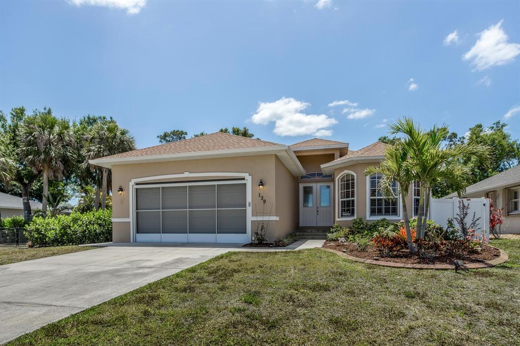 A single-story house with a tan stucco exterior, a two-car garage, and a landscaped yard — 139 CREVALLE ROAD, ROTONDA WEST, FL