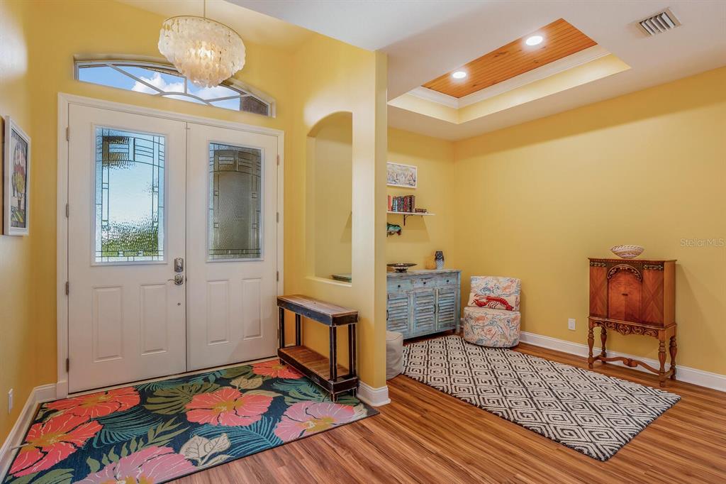 A bright entryway features yellow walls, double front doors, wood flooring, and two area rugs — 139 CREVALLE ROAD, ROTONDA WEST, FL