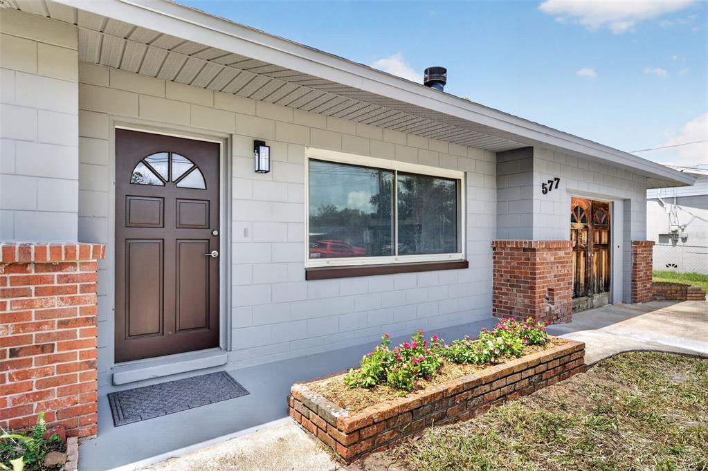 The exterior of a house features a gray block facade, brick accents, and a front garden — 577 PARKDALE COURT, DELAND, FL