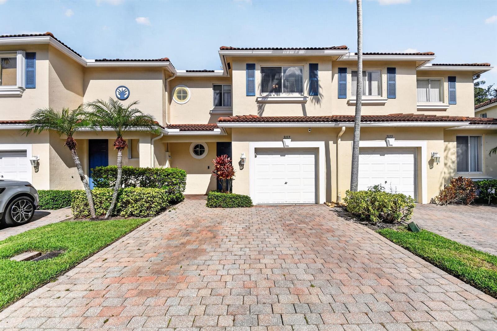 A two-story townhouse with a paved driveway, a white garage door, and blue shutters — 3117 N Evergreen Circle, Boynton Beach FL 33426, BOYNTON BEACH, FL
