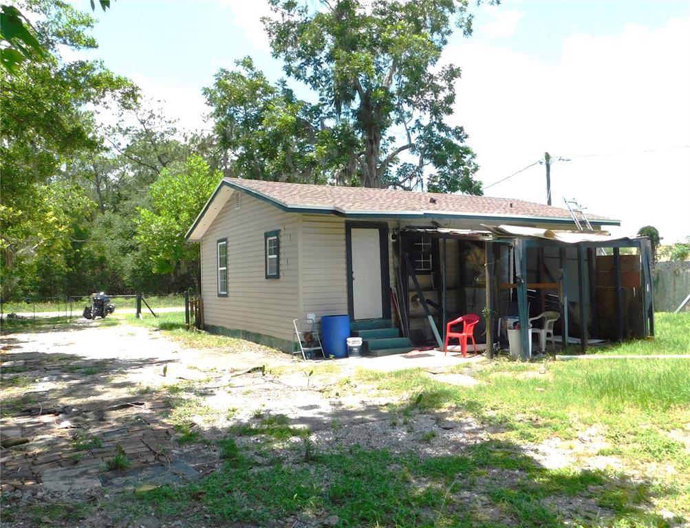 A single-story house with tan siding and a screened-in porch sits on a dirt lot — 306 FLORIDA DRIVE, PALATKA, FL