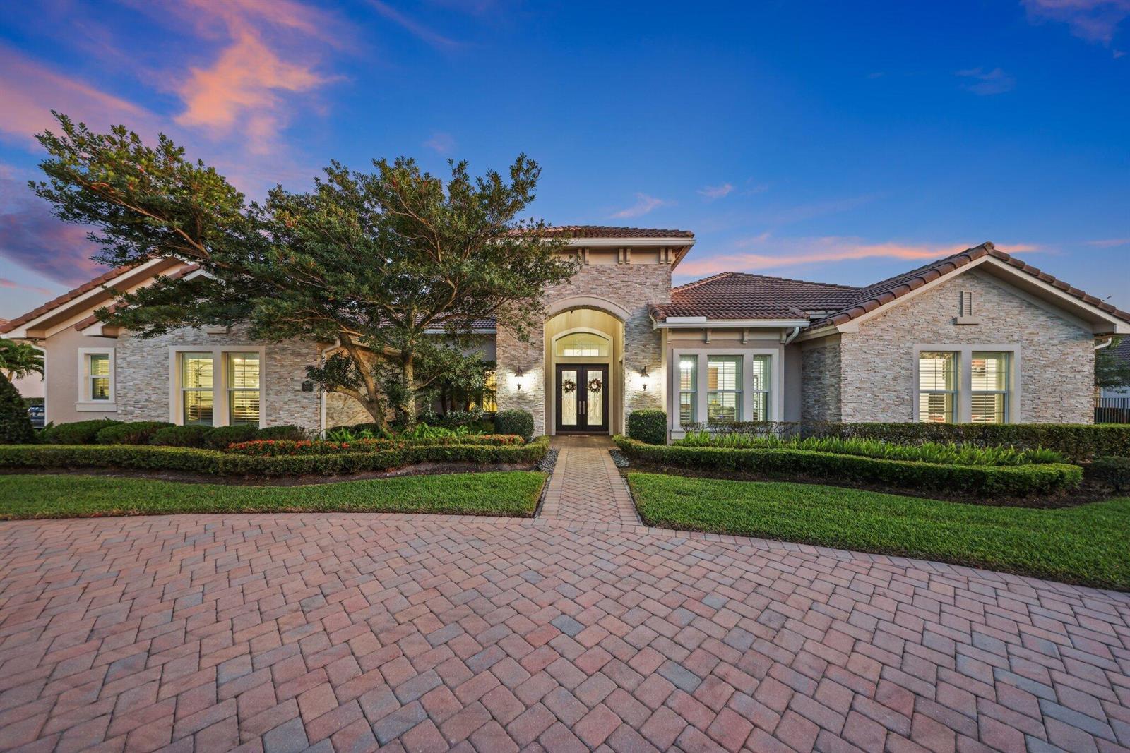 A single-story stone house with a tiled roof, arched entryway, and a brick paver driveway — 5700 N Sterling Ranch Drive, Davie FL 33314, DAVIE, FL