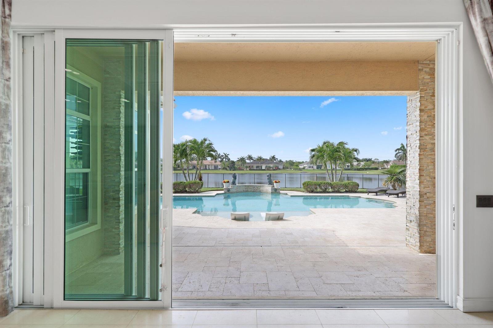A view from inside a room through large sliding glass doors to a pool patio — 5700 N Sterling Ranch Drive, Davie FL 33314, DAVIE, FL