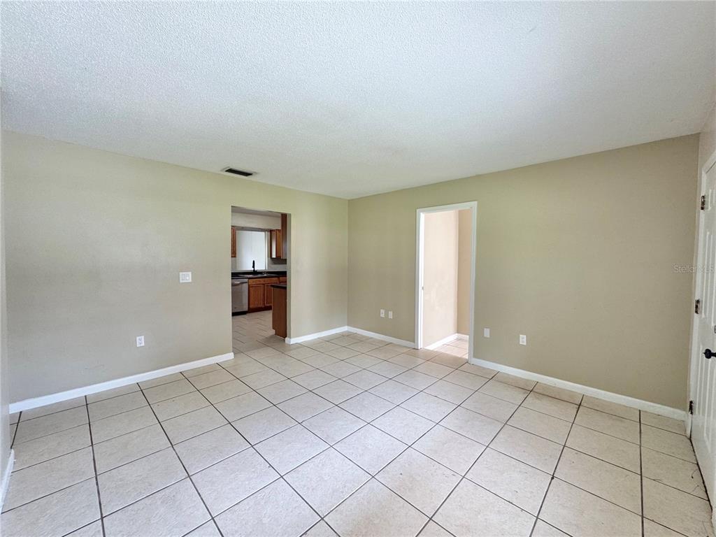 An empty room with beige walls, white baseboards, and light-colored square floor tiles — 506 THOMAS AVENUE, WINTER HAVEN, FL