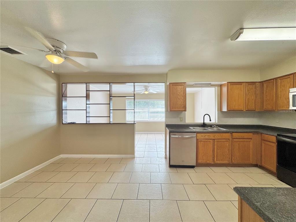 A kitchen and dining area with tile floors, wooden cabinets, and a room divider — 506 THOMAS AVENUE, WINTER HAVEN, FL
