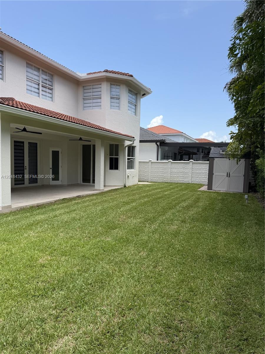 A two-story house features a covered patio, a grassy backyard, and a storage shed — MIAMI, FL