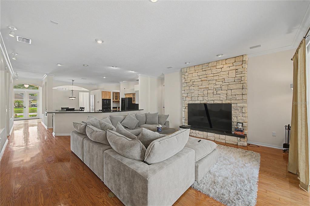 A living room features a stone fireplace, a large sectional sofa, and hardwood flooring — 18615 CHEMILLE DRIVE, LUTZ, FL