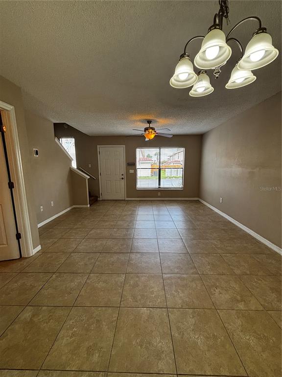 An open-concept living area features tan tile flooring, a ceiling fan, and a chandelier — 1627 LONG RIDGE COURT UNIT 270, ORLANDO, FL