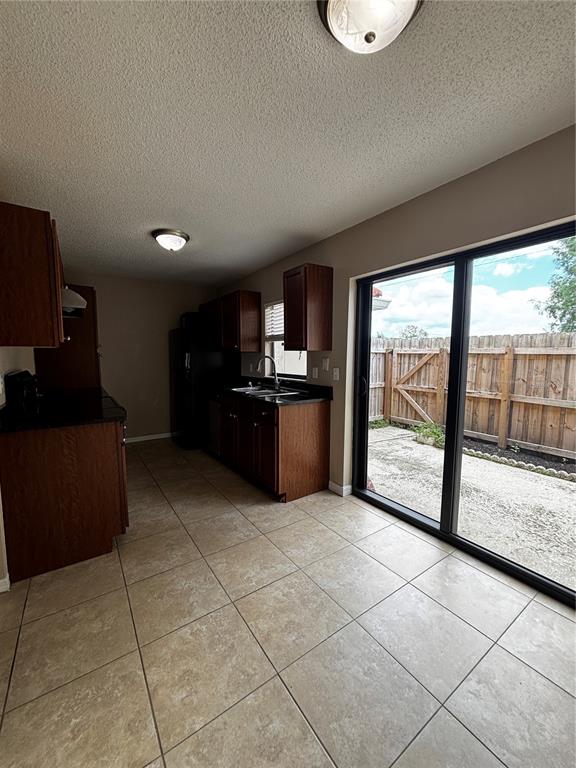 A kitchen with dark wood cabinets, black countertops, tile flooring, and a sliding glass door — 1627 LONG RIDGE COURT UNIT 270, ORLANDO, FL