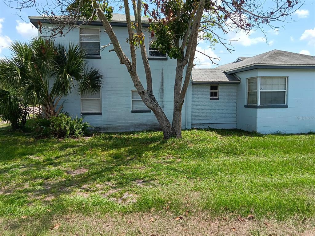 A two-story light blue concrete block house with a single-story wing and a large tree — 1011 NE 2ND STREET, MULBERRY, FL