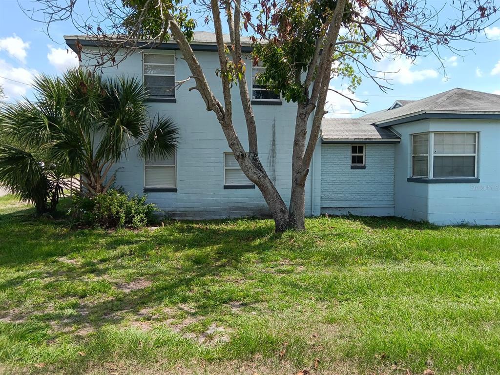 A two-story light blue painted brick house with a single-story wing and a large tree — 1011 NE 2ND STREET, MULBERRY, FL
