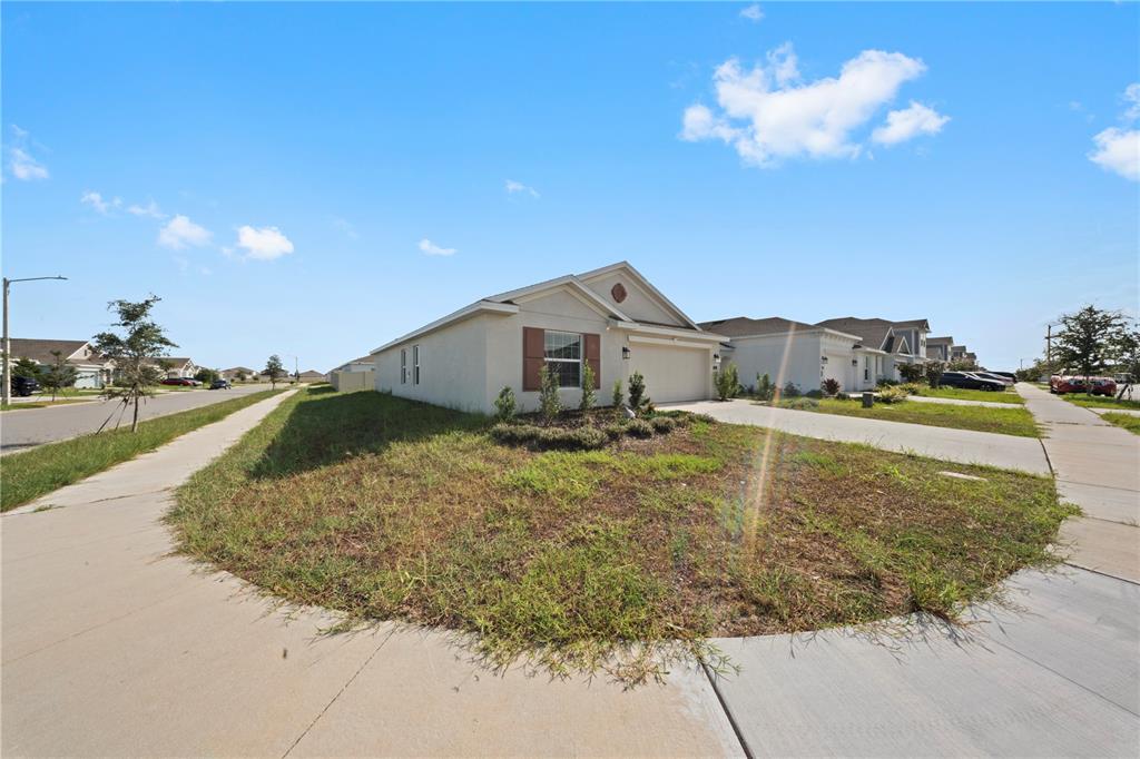 A single-story house with a beige exterior and a two-car garage sits on a corner lot — 501 SEA TURTLE LANE, HAINES CITY, FL