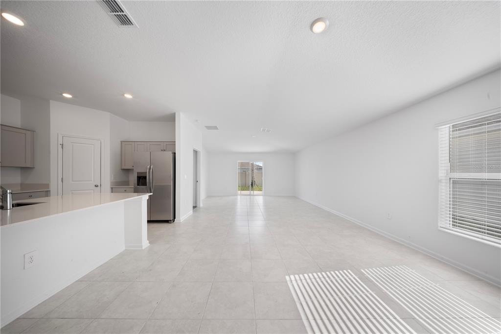 An open-concept kitchen and living area with white walls, tile flooring, and stainless steel appliances — 501 SEA TURTLE LANE, HAINES CITY, FL