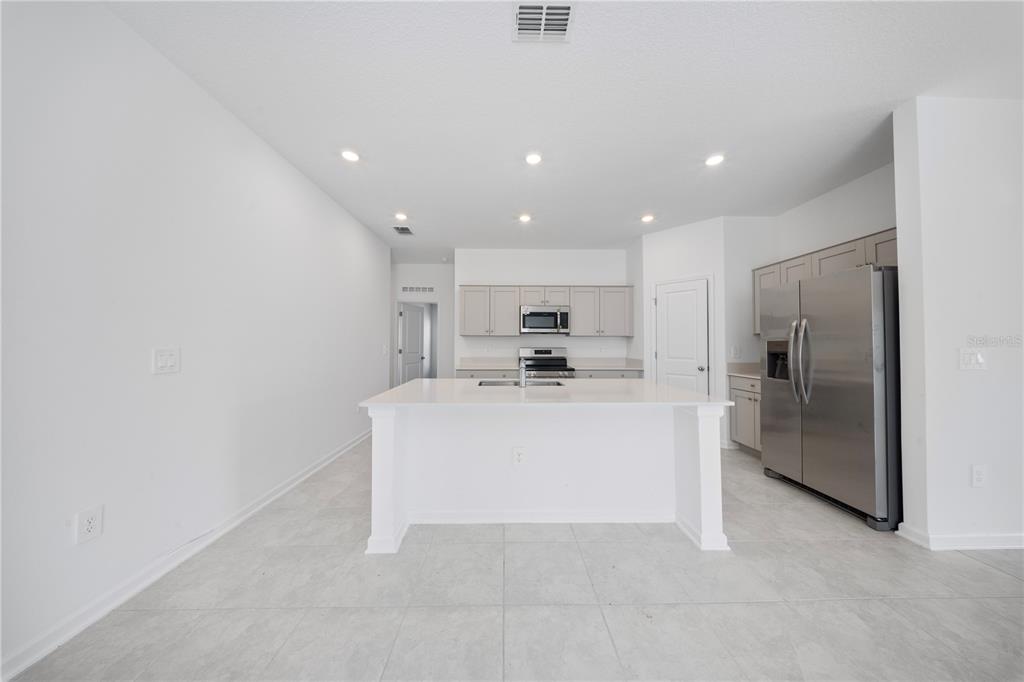 A modern kitchen features a white island, stainless steel appliances, and light-colored cabinetry — 501 SEA TURTLE LANE, HAINES CITY, FL