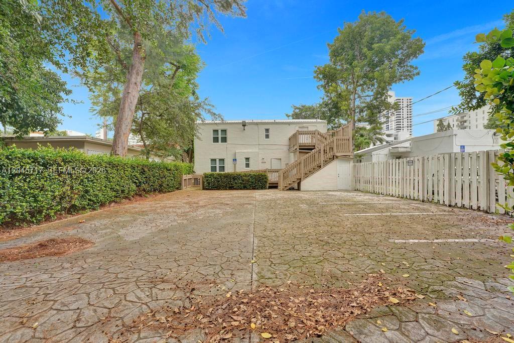 A paved parking lot sits in front of a two-story building with an exterior wooden staircase — 1225 Alton Rd, Miami Beach FL 33139, MIAMI BEACH, FL