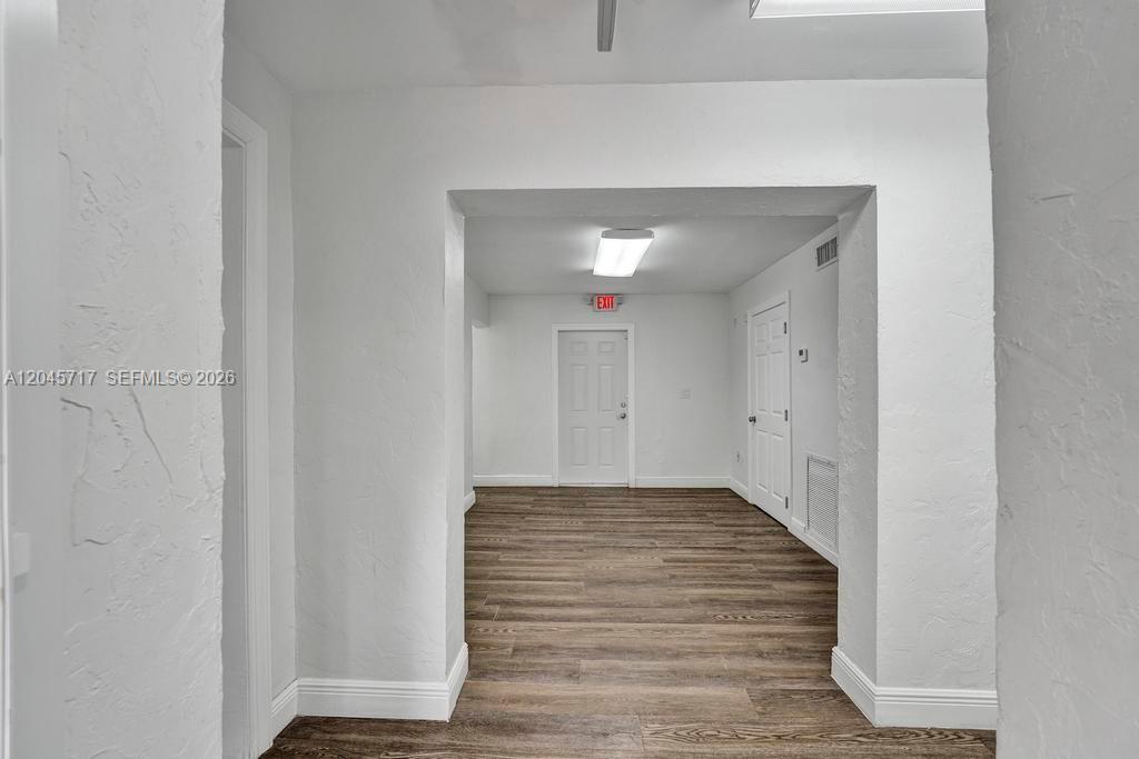 A hallway leads to a room with white walls, wood-look flooring, and two doors — 1225 Alton Rd, Miami Beach FL 33139, MIAMI BEACH, FL