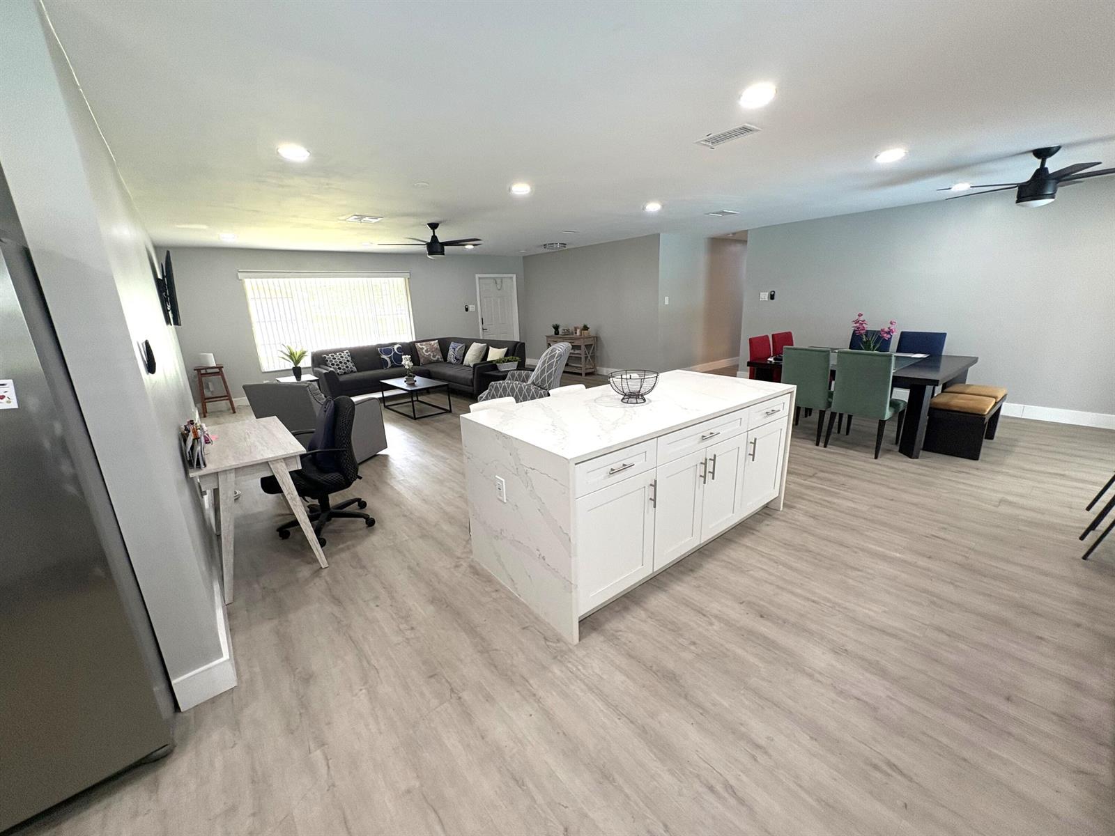 An open-concept living area features a kitchen island, dining table, and gray wood-look flooring — 1401 NW 75th Terrace, Plantation FL 33313, PLANTATION, FL