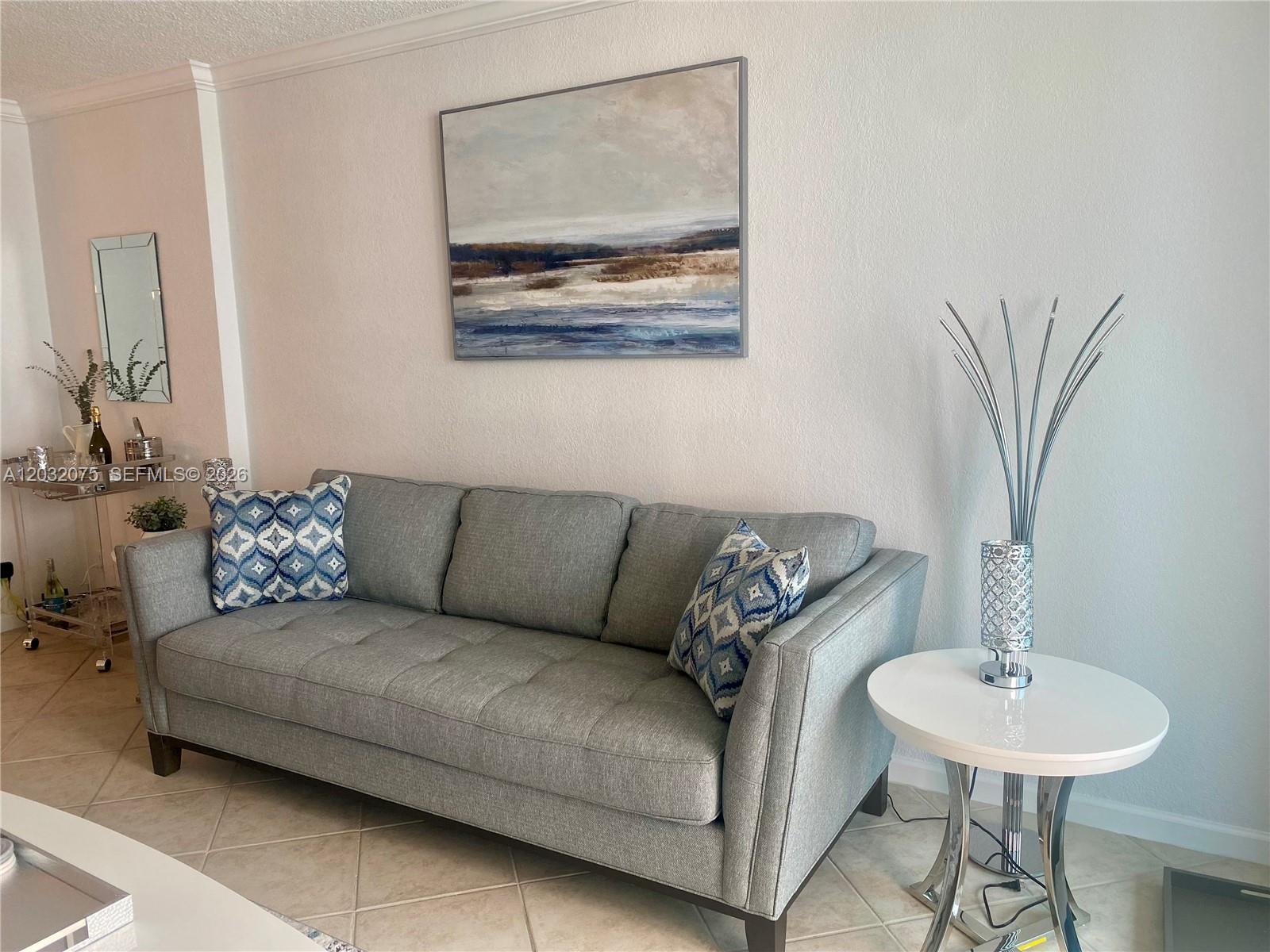 A gray sofa sits in a living room with a landscape painting and side table — 2501 S Ocean Dr, Hollywood FL 33019, HOLLYWOOD, FL