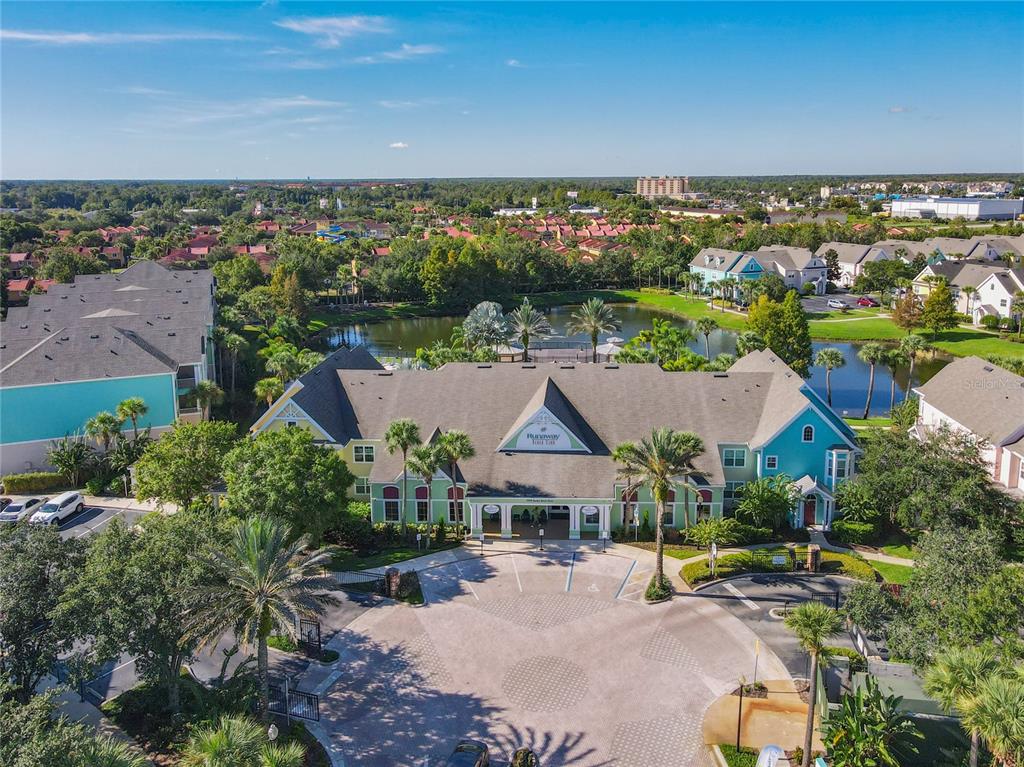 An aerial view shows a multi-story clubhouse with a green facade beside a lake — 3002 BONFIRE BEACH DRIVE UNIT 202, KISSIMMEE, FL